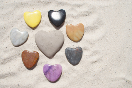 Different colored stone hearts in the sandの写真素材