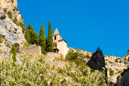 View up to the old chapel Notre Dame de Beauvoir at the foot of the historic mountain village of Moustiers-Sainte-Marie in southern France in the summer in front of a bright blue skyの写真素材