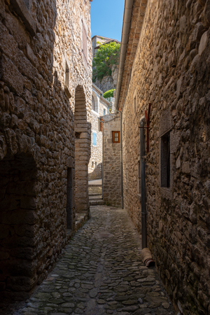 View into a narrow and dark cobbled alley in the old French village Labeaume on the river Ardeche in Franceの写真素材