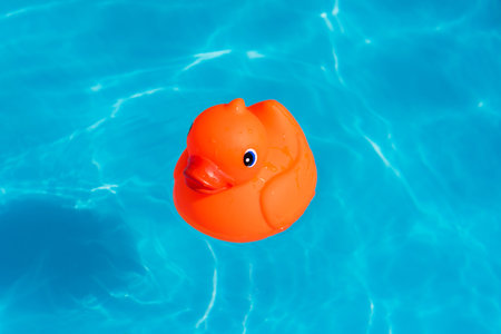 A single orange rubber duck floats in a paddling pool