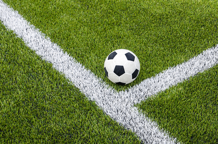 The soccer football on the white line in the artificial green grass fieldの写真素材