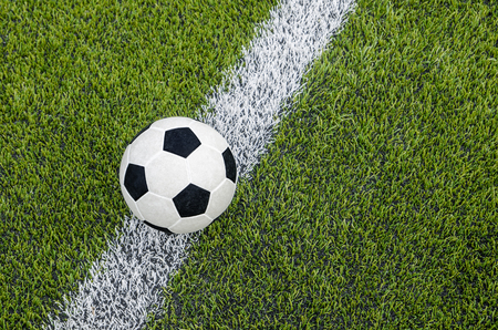 The soccer football on the white line in the artificial green grass fieldの写真素材