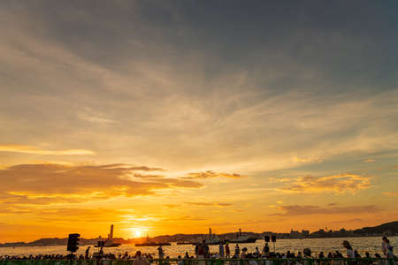 People waiting for a fireworks display in The Kanmon Strait illuminated by the sunset and a beautiful skyの写真素材