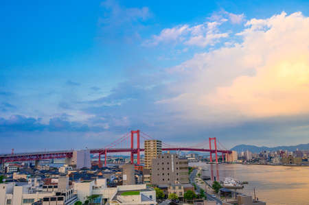Beautiful red suspension bridge and cityscape illuminated by sunsetのeditorial素材