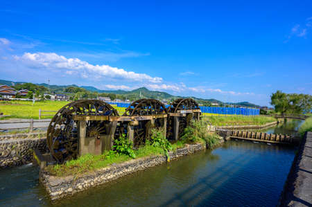 An old summer water mill that brings up beautiful water under the blue sky (Asakura City, Fukuoka Prefecture)の写真素材
