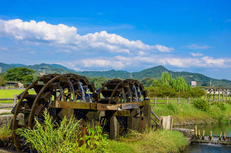 An old summer water mill that brings up beautiful water under the blue sky (Asakura City, Fukuoka Prefecture)の写真素材