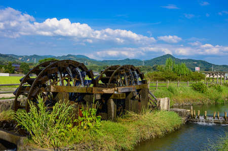 An old summer water mill that brings up beautiful water under the blue sky (Asakura City, Fukuoka Prefecture)の写真素材