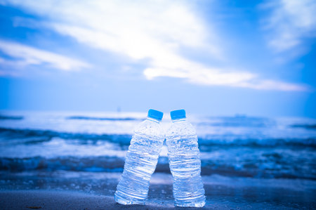 Plastic bottles of water on the beach with blue sky background.の写真素材