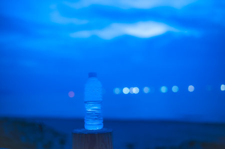 Bottle of water on the beach at night. Selective focus.の写真素材