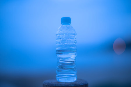 Bottle of water on the wooden table with blue background, soft focus