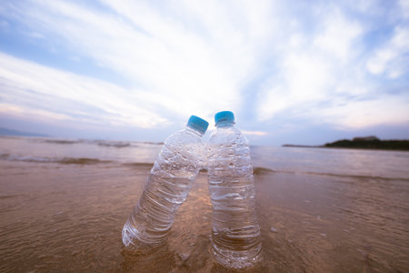 Plastic bottle on the beach at sunset time. Concept of water pollution.の写真素材