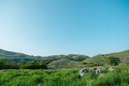 Mountain landscape with green grass, blue sky and white clouds.の写真素材