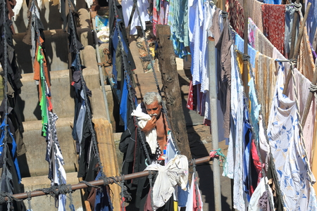 Mumbai India - October 12, 2017: Unidentified man hangs laundry in Dhobi Ghat laundromat Mumbai India.のeditorial素材