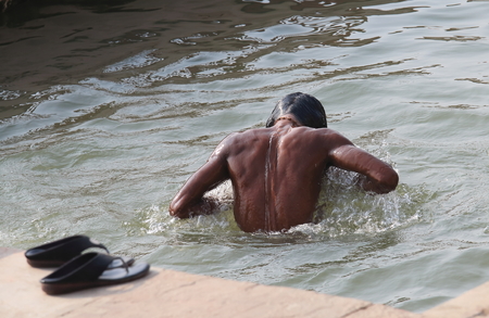 A man bathes in Ganges river Varanasi India.の写真素材