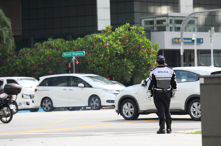 Singapore-November 15, 2018: Unidentified police officer watch downtown traffic in Singapore.のeditorial素材