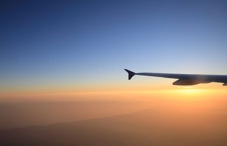 Sunset flight view with airplane wing silhouetteの写真素材