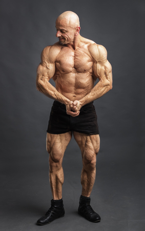 Athlete in front pose. Bodybuilder showing muscles and motivating to trainingの写真素材