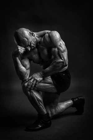Professijnal bodybuilder and fitnes model posing in studio like a philosopher. Black and white low kay version.の写真素材