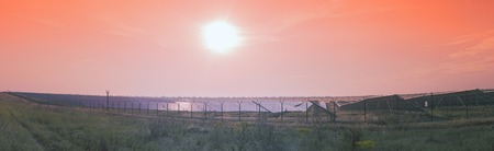 Panoramic view of the field of solar panels. The sun rose above the horizon, the rays falling on the solar panels and plants.の写真素材