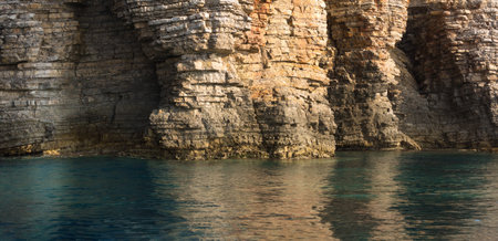 Close up Sea cliff in Montenegro, Layered rocks and stones with turquoise blue Adriatic sea water