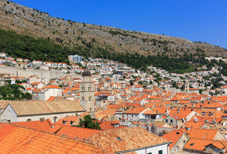 View of Dubrovnik from the fortress wall. The old city smoothly turns into a modern one. Orange roofs of houses, forest, mountain, blue sky. Croatiaの写真素材