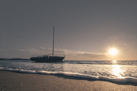 Sailing boat on the beach at sunset. Toned image.