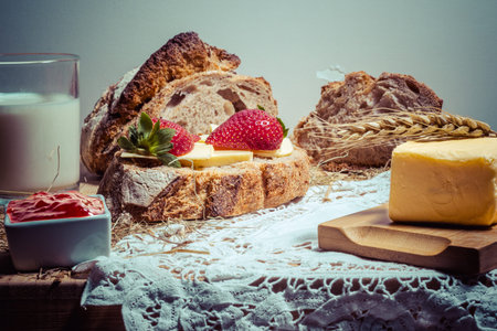 Rye bread with butter, strawberries and honey on a wooden board
