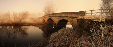 bridge in morning mist fog or haze. panoramic image of old stone construction