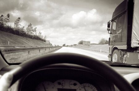 driving on motorway, view of road, steering wheel and truck whilst overtakingの写真素材