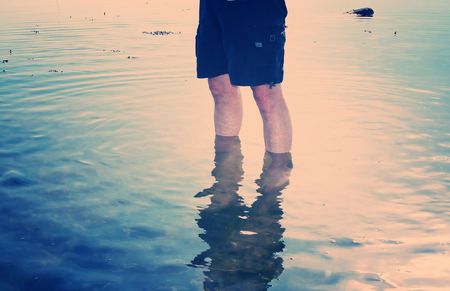 paddling legs in water by seaside. nostalgic cross processed image of holiday memoriesの写真素材