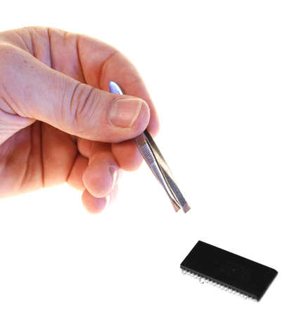 Ram or computer chip repair. hand with tweezers reach for component isolated on whiteの写真素材