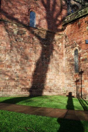 cross in cemetary graveyard, silhouette of graves against church wallの写真素材