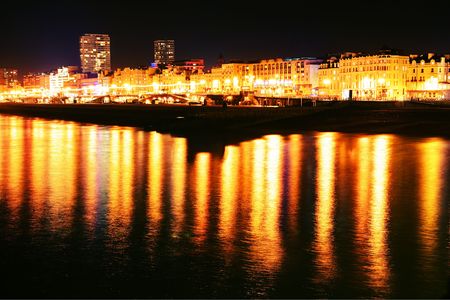 brighton seaside town in england. shoreline at night with sea and lit hotelsの写真素材