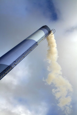 Chimney with smoke from industry or factory burning fuel and creating pollution to environmentの写真素材