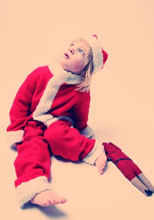 santa clause or father christmas child. boy with long hair in red xmas suit cross processedの写真素材