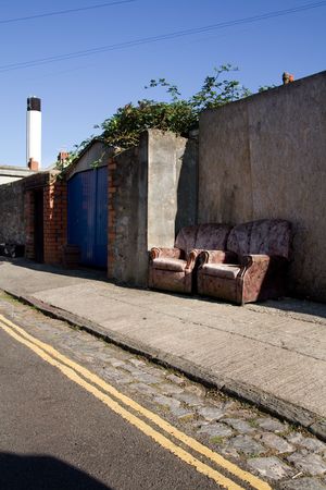 armchairs on street or pavement in urban town area.trashed furniture, rubbish or litter by the roadの写真素材