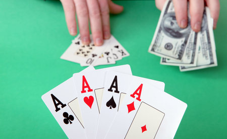 game of cards or poker. gambling and winning money or losing. hand with four aces and stak of dollar...