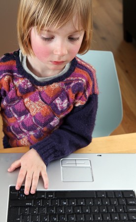 Child playing with computer. Blonde boy typing or working on laptop keyboard. kid concentrating on pcの写真素材