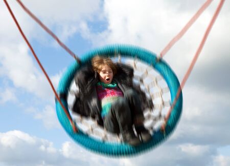 Child on swing against blue sky. Swinging boy moving at speed on playground rideのeditorial素材