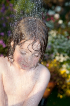 child playing with hosepipe in garden. boy play water games in summer on lawnの写真素材
