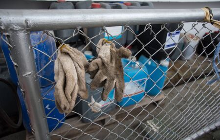 worker with gloves on wire brushing a chain link fenceの写真素材