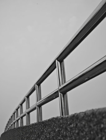 Black and white photo of the metal fence with the sky in the backgroundの写真素材