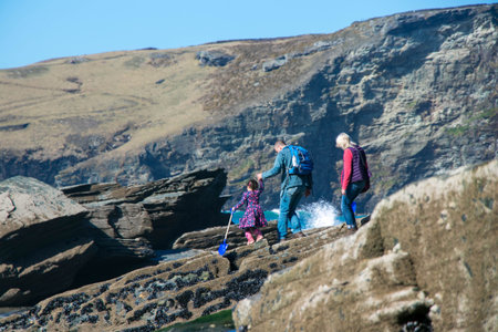 Family carefully cross rocks to make their way to the sandy beach