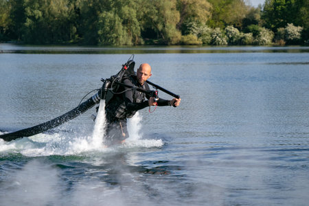 Thrillseeker, water sports lover, athlete strapped to Jet Lev, levitation hovers over lake with blue...