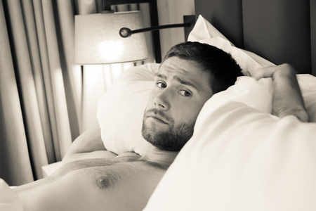Shirtless sexy hunky man with beard lies naked in bedの写真素材