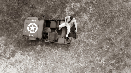 Overhead, drone, looking down on Male army officer in uniform resting on back of military vehicleの写真素材