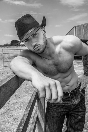 Sexy, handsome, hunky shirtless cowboy with hat abs and pecs looks at cameraの写真素材