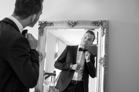 Man wearing tuxedo in hotel room talking on mobile phone, cellphoneの写真素材