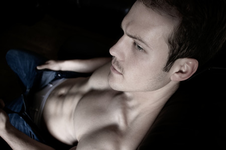 Good looking man with pecs and six pack abs sitting on armchairの写真素材