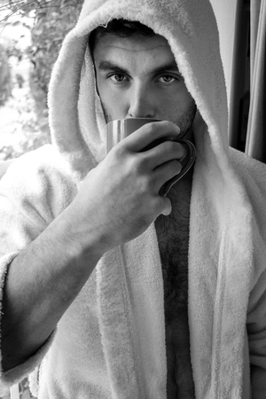 Good looking mand drinking coffee in front of windowの写真素材